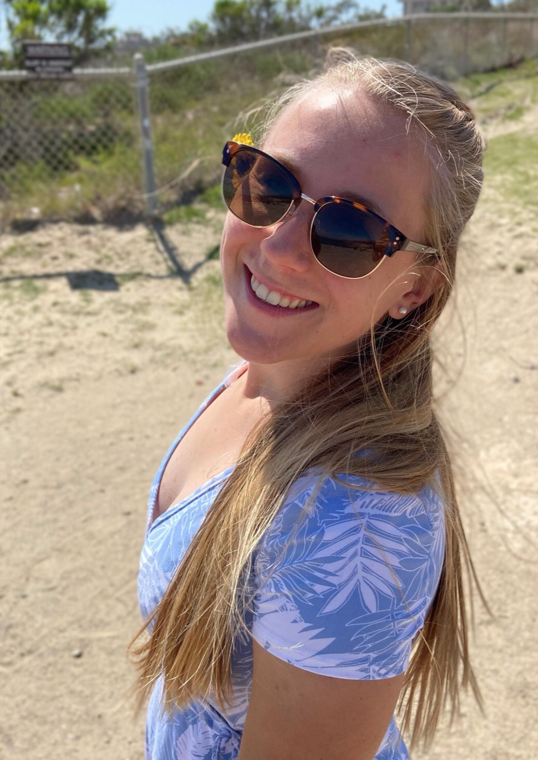 Ashley Petrie stands along the bluffs at UC Santa Barbara, smiling and wearing sunglasses