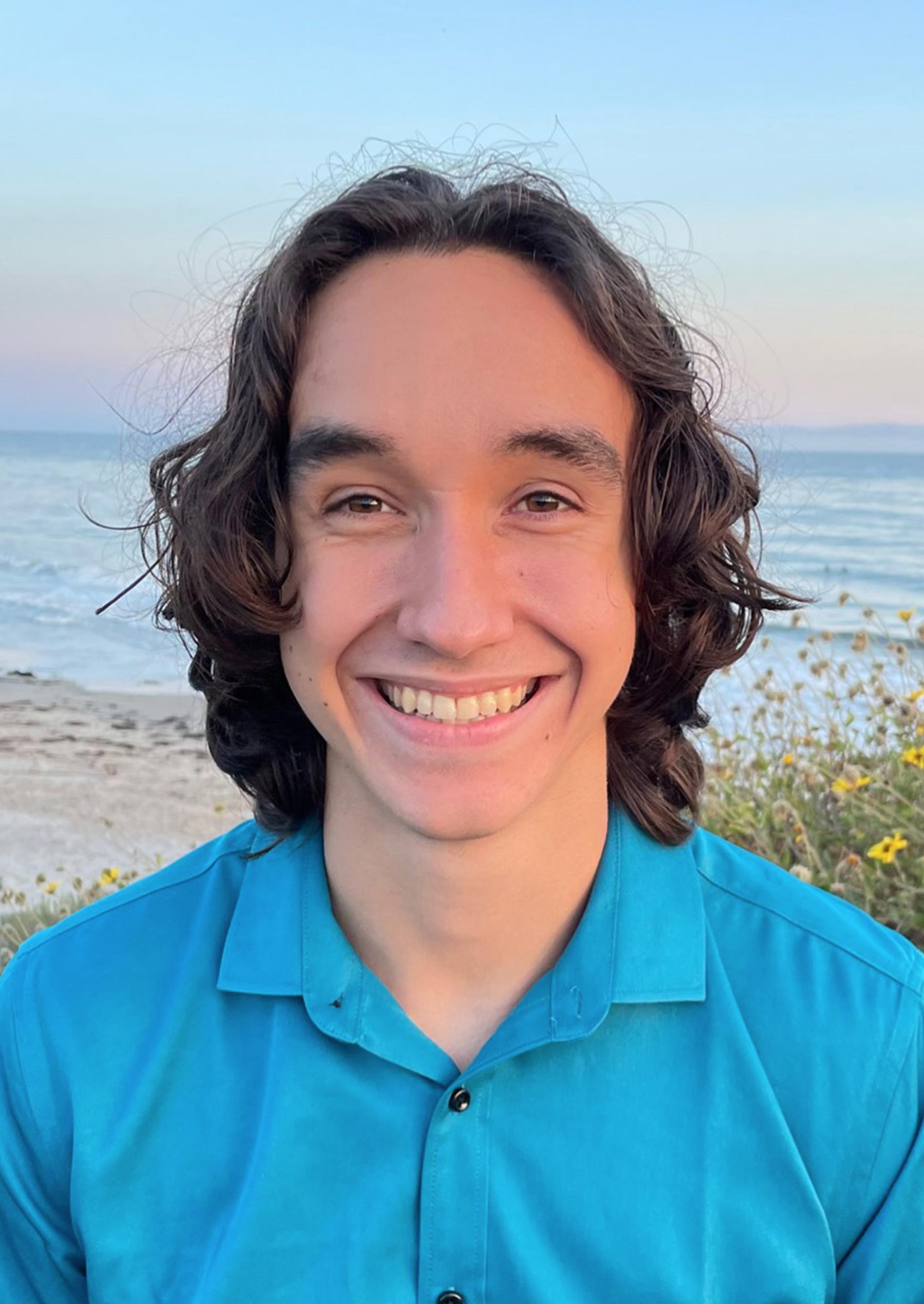 Sean Benevedes smiles with the beach and ocean behind him