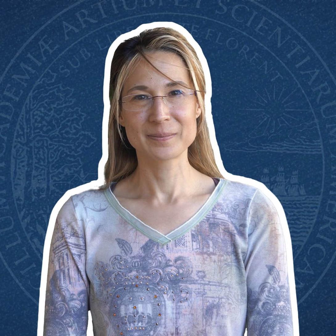 Irene Beyerlein wears a blue top with the seal of the University behind her
